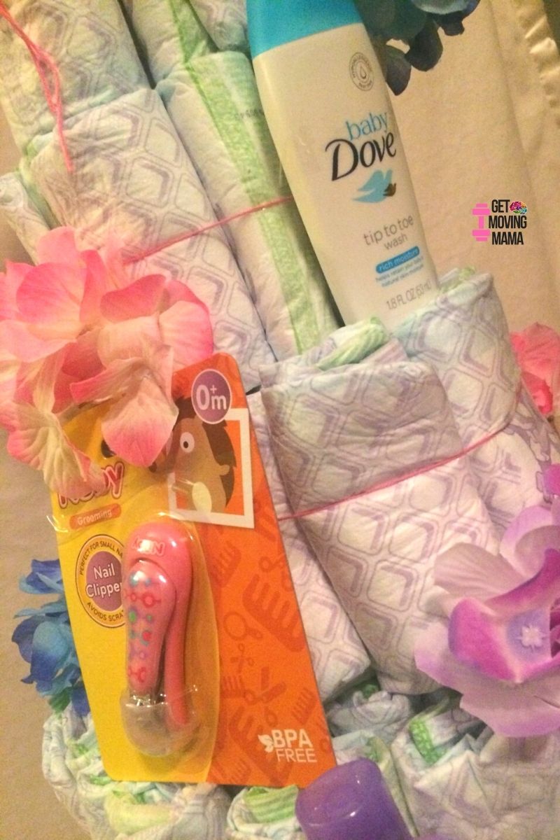 A picture of a diaper cake layer with Dove body wash, Nuby nail clippers and flowers.