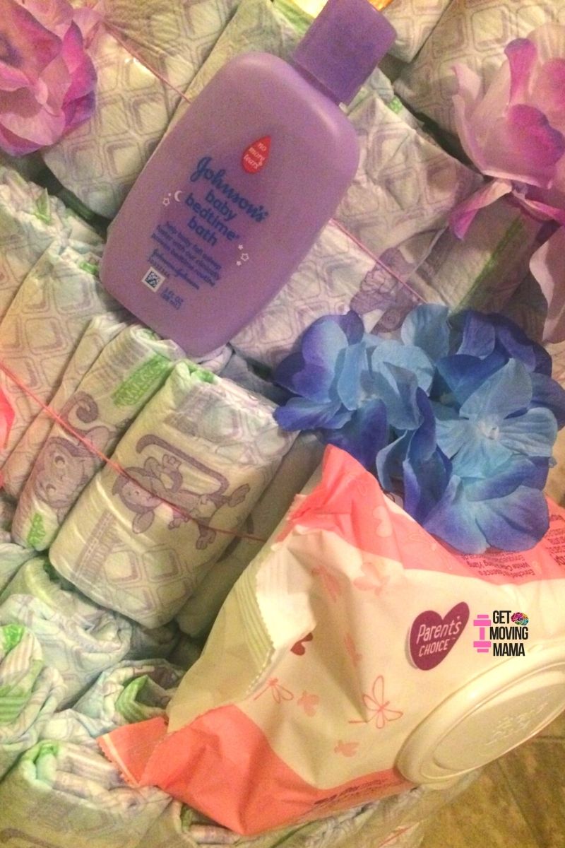A picture of a diaper cake layer with Dove body wash, J&J baby bath, wipes and flowers.