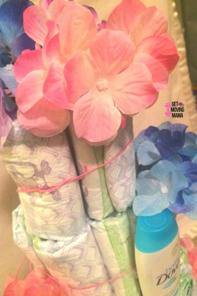A picture of a diaper cake layer with Dove body wash and flowers.