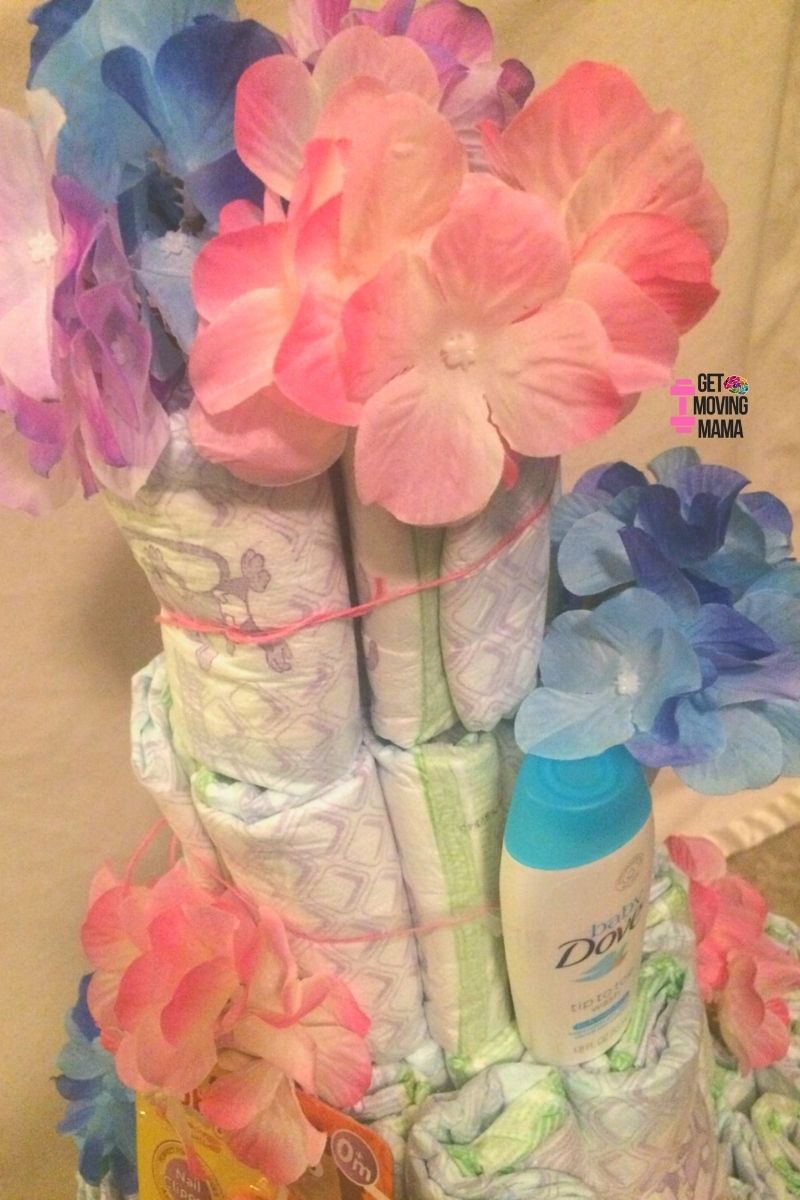 A picture of a diaper cake layer with Dove body wash and flowers.