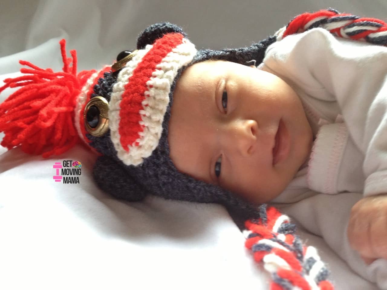 A picture of a baby with a crochet sock monkey hat.